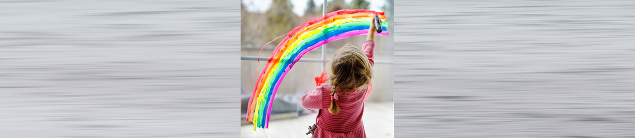 young girl painting a bright rainbow in a window